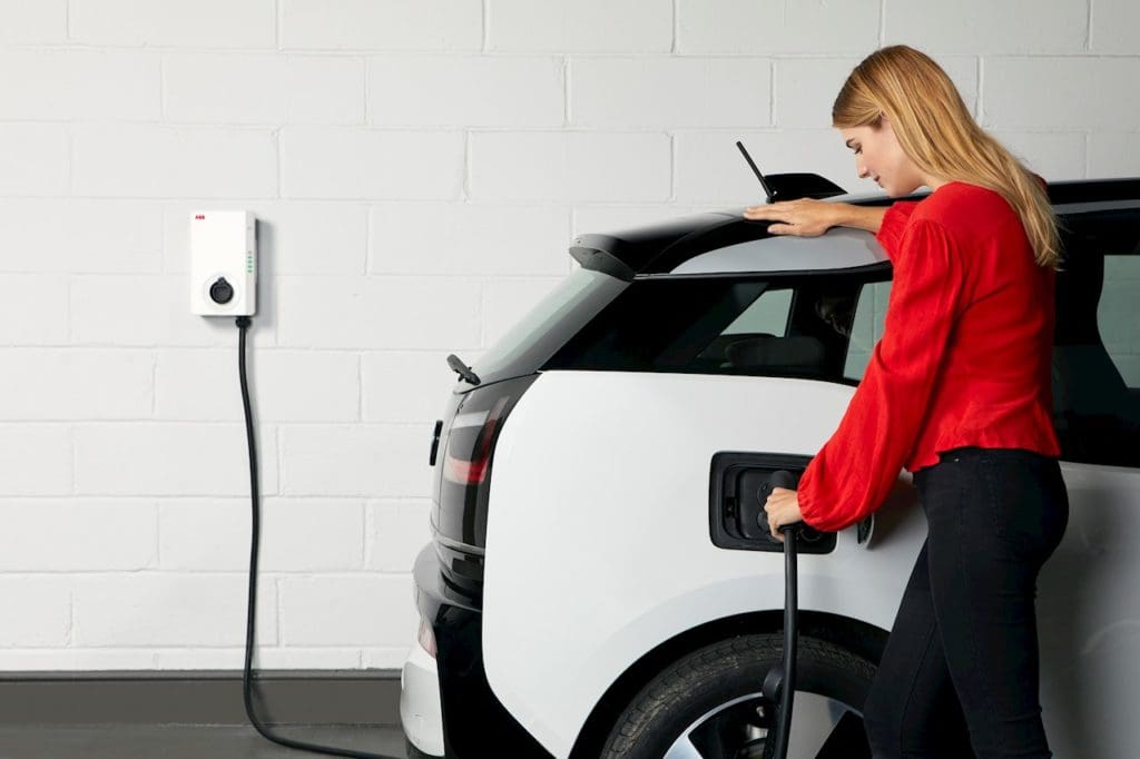 Lady charging a modern SUV in her home garage with an ABB terra wallbox charger