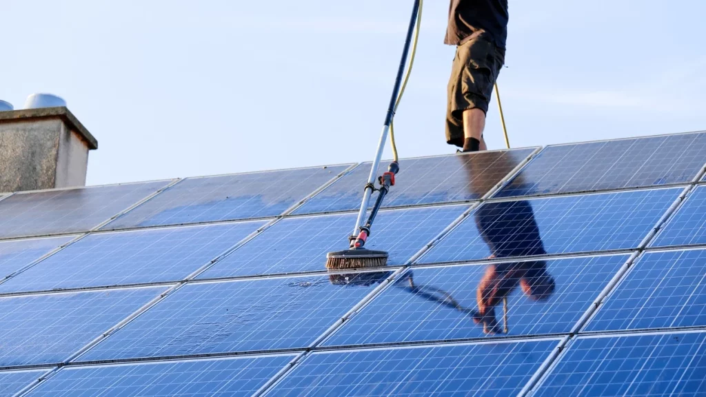 Man cleaning a solar panel on the roof