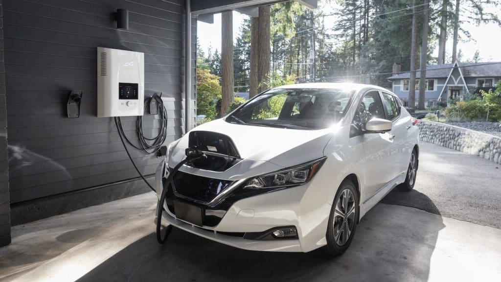 White electric vehicle pluged into ev charger